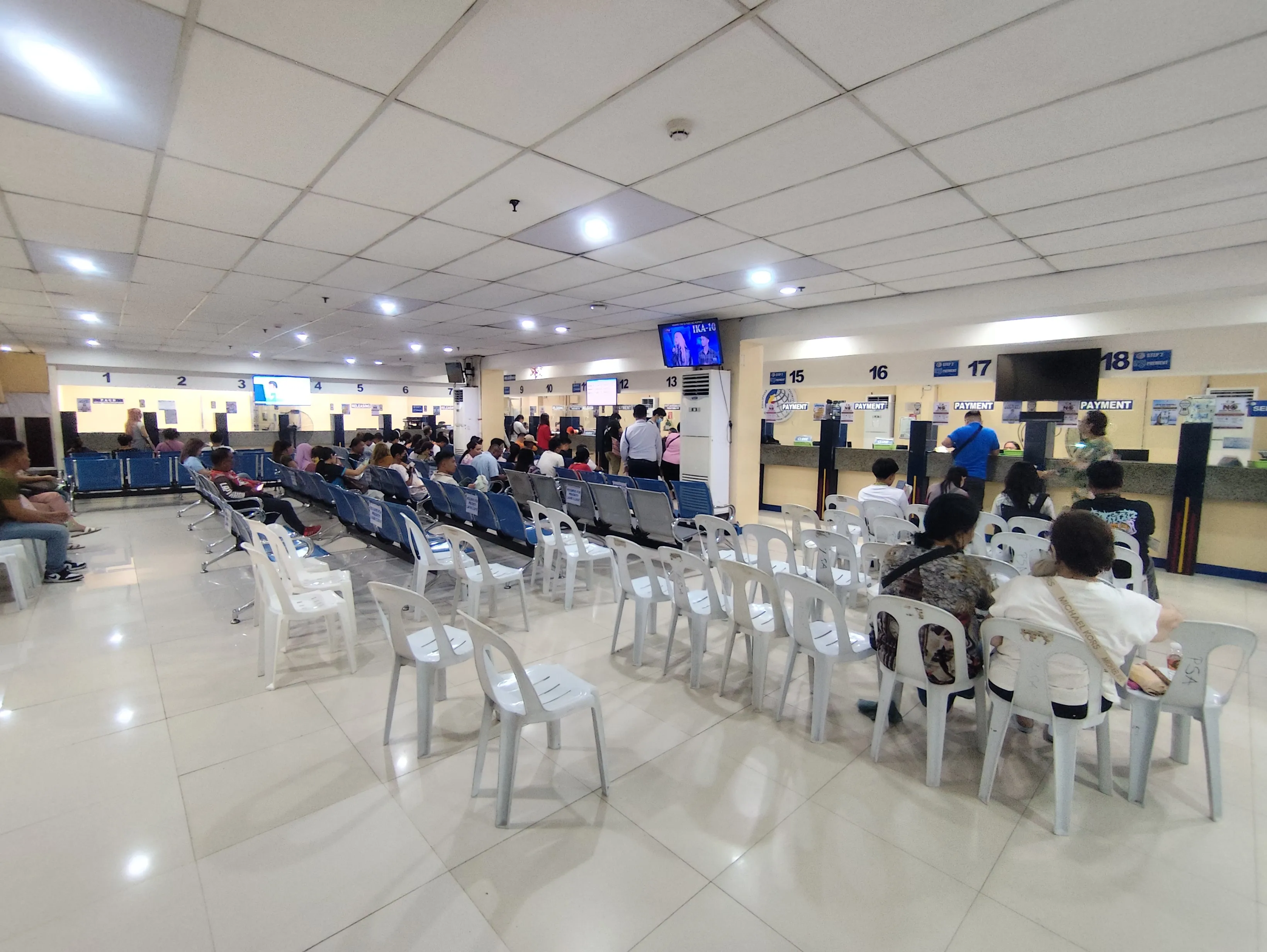 Large waiting area with white chairs and PAYMENT counters visible at the back